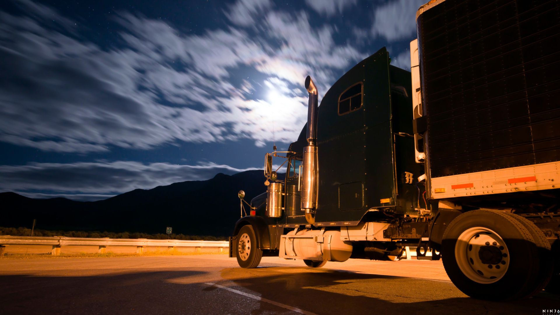 Refrigerated truck parked under a moonlit sky at night